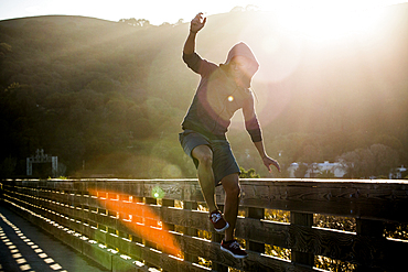 Mixed Race man jumping near railing on footbridge