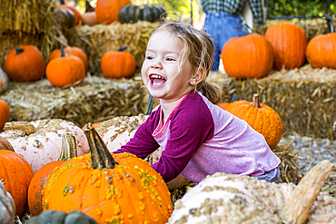 Smiling Caucasian girl playing in pumpkin patch