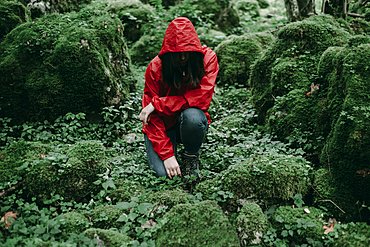 Caucasian woman kneeling in lush forest