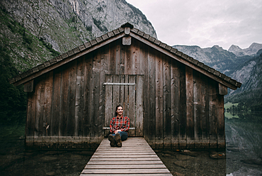 Caucasian woman sitting on dock at remote cabin