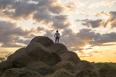 Caucasian man standing on rock pile at sunset