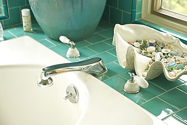 Decorative shells on aqua tile bathroom counter near sink