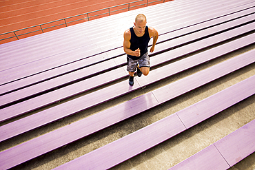 Caucasian man running on purple bleachers