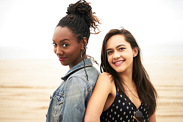 Smiling women back to back on beach