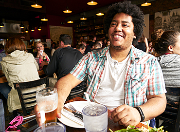 Smiling man drinking beer in restaurant