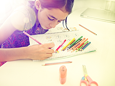 Mixed Race girl drawing faces in notebook