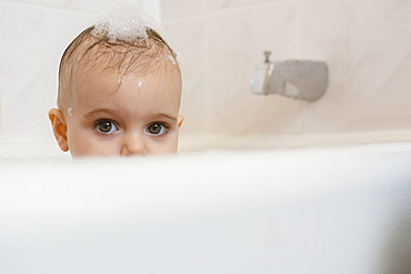 Caucasian baby girl in bathtub with soap in hair