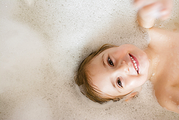 Caucasian girl smiling in bubble bath