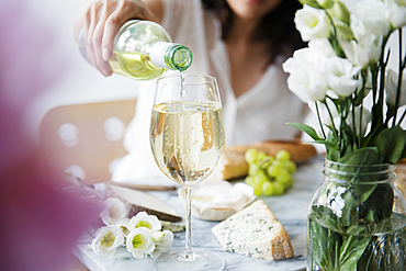 Hispanic woman pouring wine at table