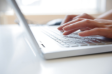 Hands of Hispanic woman typing on laptop