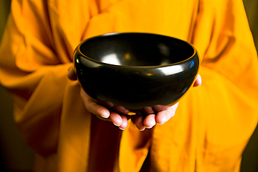 Monk in orange robe holding black bowl