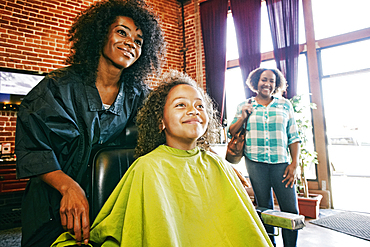 Smiling hairdresser and customers in hair salon