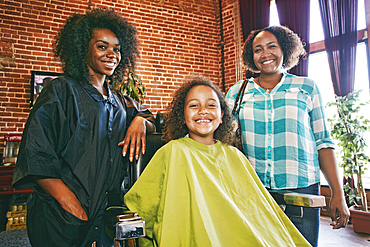 Smiling hairdresser and customers in hair salon