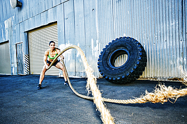 Mixed Race woman working out with heavy ropes outdoors