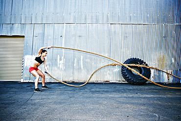 Mixed Race woman working out with heavy ropes outdoors