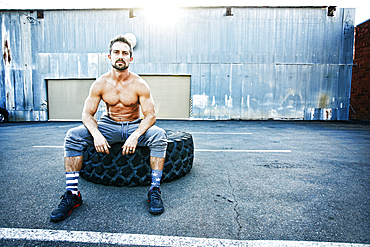 Caucasian man sitting on heavy tire outdoors