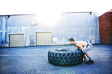 Caucasian man working out with heavy tire outdoors