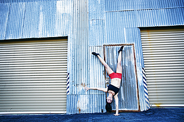 Caucasian woman doing one-handed handstand outdoors