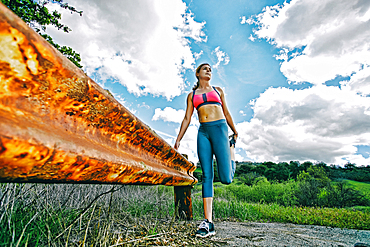 Caucasian woman leaning on rusty barrier stretching leg