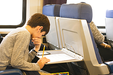 Mixed Race boy doing homework on train