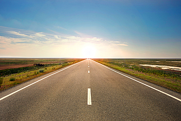 Sunset over distant empty highway