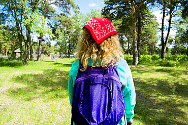 Woman wearing bandana carrying backpack in park