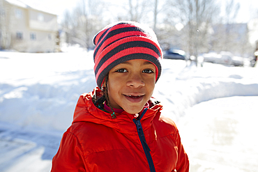 Smiling Mixed Race girl wearing hat and coat in winter