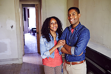 Smiling couple posing in empty house