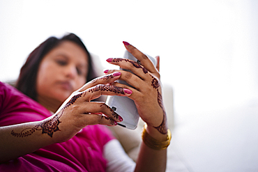 Woman with henna tattoos on hands texting on cell phone