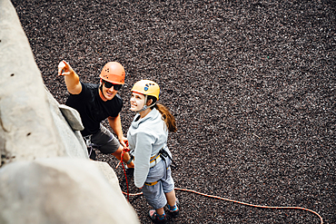 Caucasian man and woman pointing at rock climbing wall