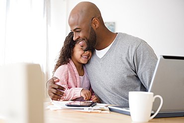 Father hugging daughter at table