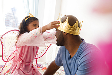 Daughter wearing costume placing crown on father