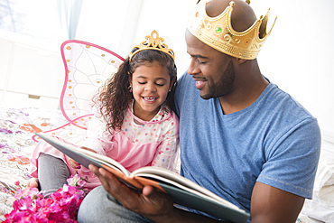 Father ready story to daughter on bed