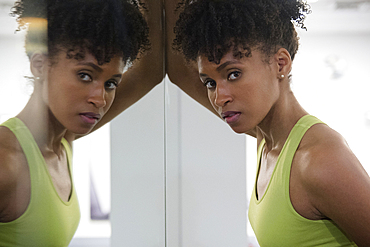 Serious Black woman leaning on mirror wall