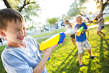 Caucasian boys and girls playing with squirt guns