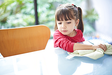 Hispanic girl cleaning table with towel