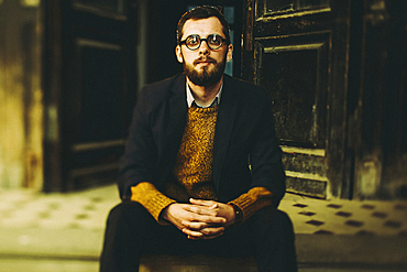 Caucasian man with beard sitting on front stoop