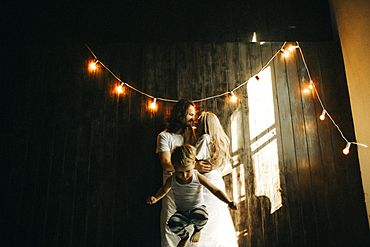 Caucasian couple hugging near boy under string lights