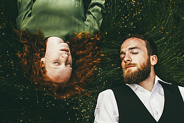 Caucasian couple laying in grass