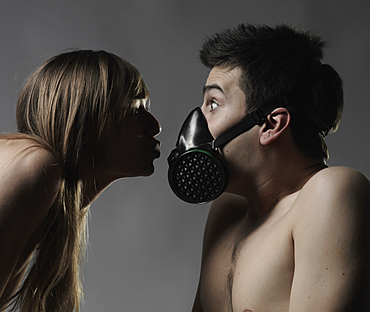 Naked Caucasian woman breathing on man wearing pollution mask