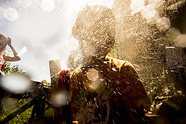 Back lit Mari boy spraying hose