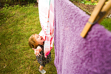 Caucasian baby girl playing with towels on clothesline