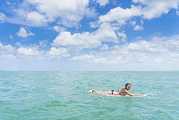 Caucasian woman paddling on surfboard in ocean