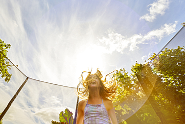 Low angle view of Caucasian girl jumping on trampoline