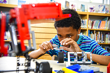 Boy assembling plastic blocks in library