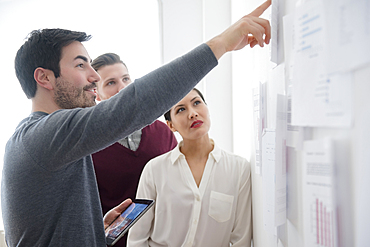 Business people talking about paperwork on wall