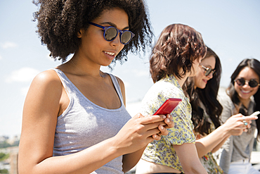 Women texting on cell phones outdoors