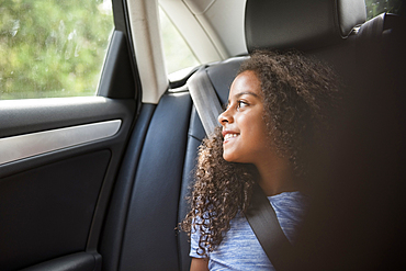 Smiling Hispanic girl in car looking out window