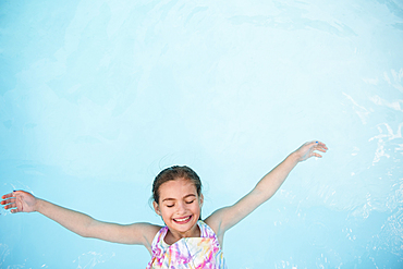 Smiling Caucasian girl floating in swimming pool