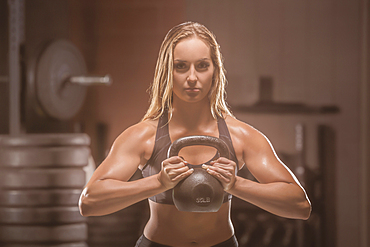 Caucasian woman lifting kettlebell in gymnasium